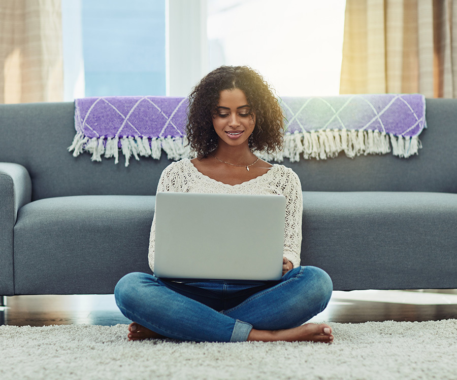 A woman applies for a mortgage using a laptop in front of her couch