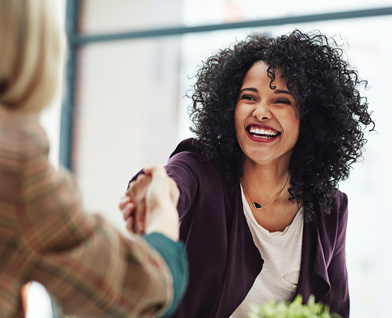 A smiling woman shakes the hand of her banker